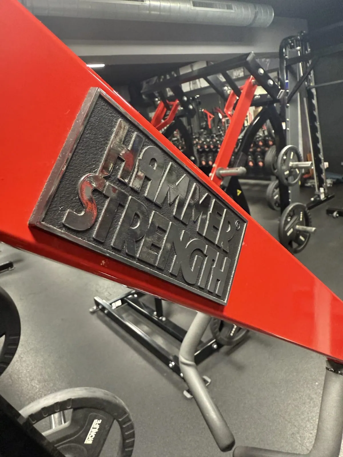 Logo Hammer Strength na červenom stroji