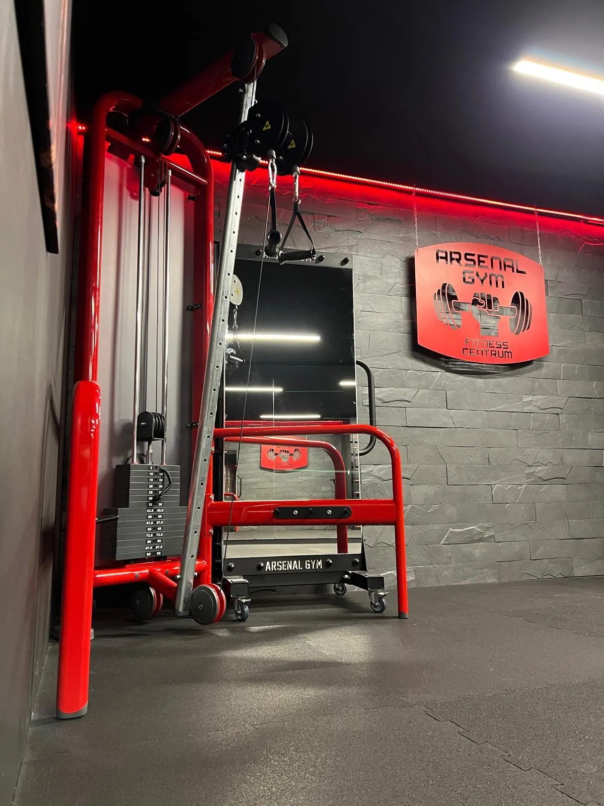 Kladkový stroj pri stene s logom Arsenal Gym